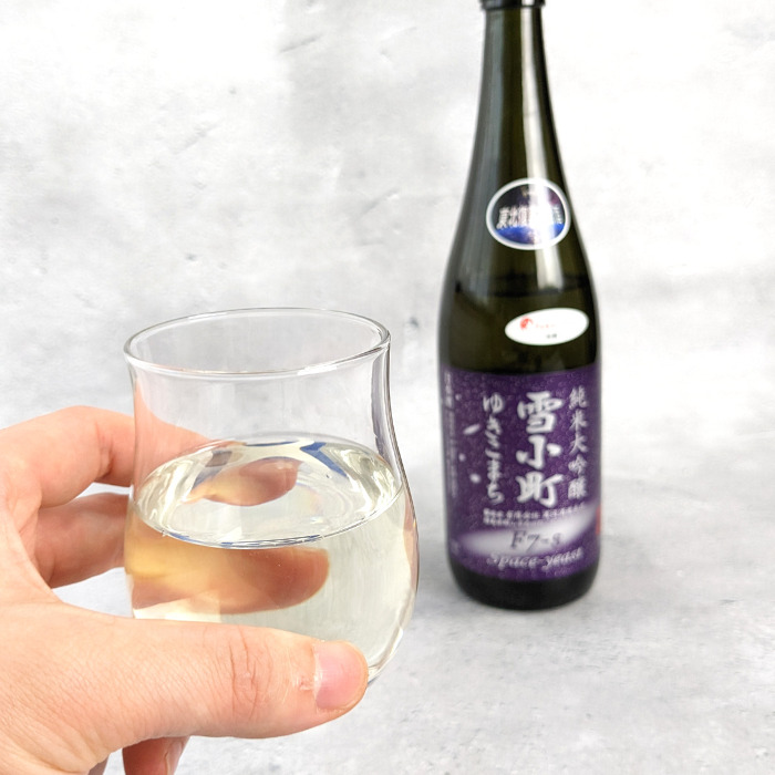 fukunomoで届いた日本酒、渡辺酒造本店「雪小町 純米大吟醸」を入れたグラスを持っている様子