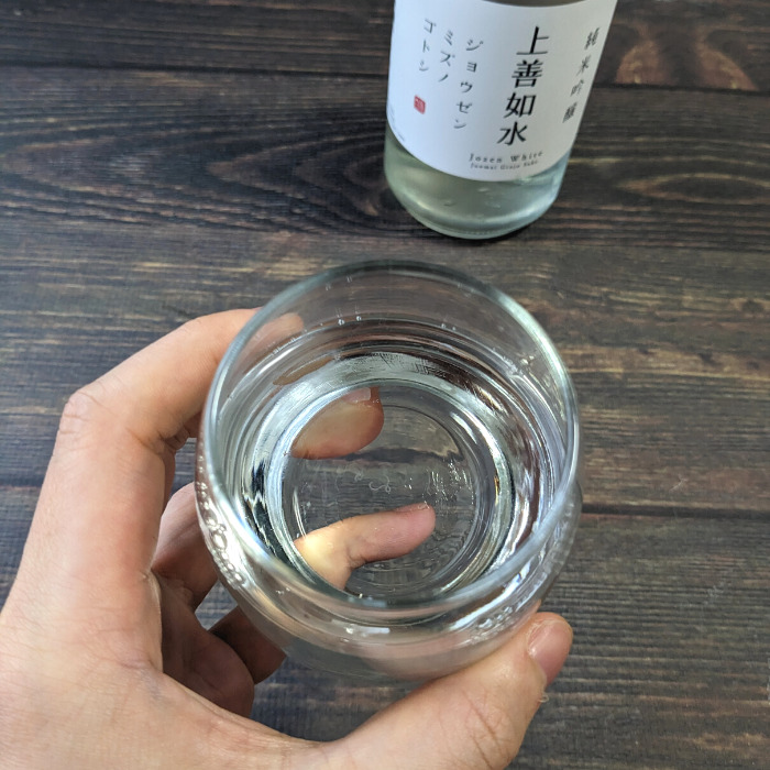 白瀧酒造「上善如水（720ml）」を入れたグラスを持っている様子